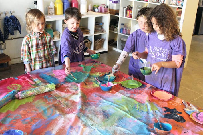 Kids painting a collaborative mural art canvas.
