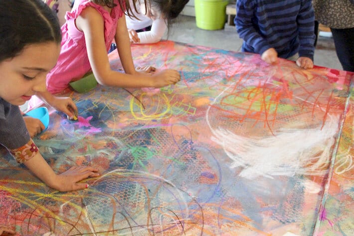 Drawing with chalk pastels for a collaborative mural art project.