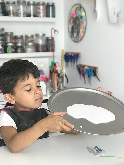 Spreading glue on pan for an easy chalk art activity.