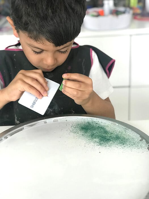 Scraping chalk pastels with a plastic card for an easy chalk art activity.