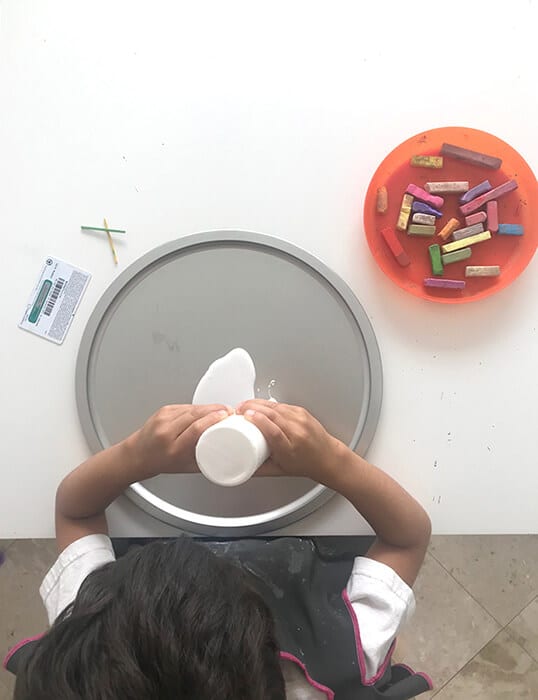 Spreading glue in pan for easy chalk art activity.