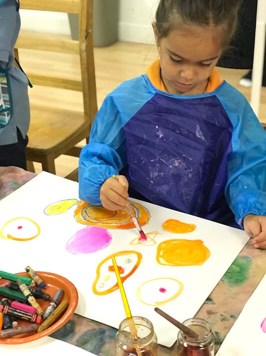 Boy painting colorful circles with watercolor paint for Yayoi Kusama Inspired Dot Paintings for Kids