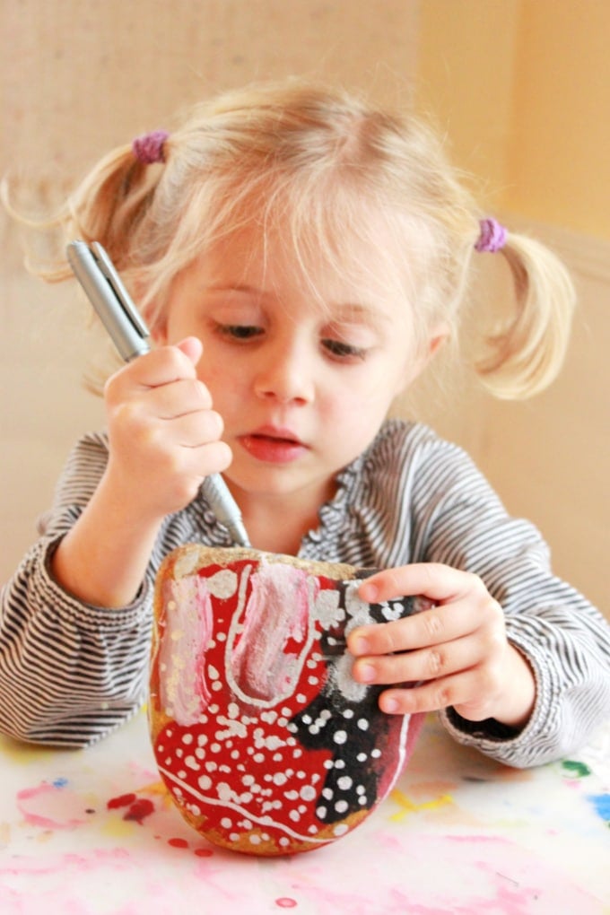 child drawing on rock