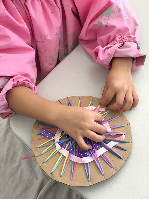 A cardboard weaving loom made with yarn