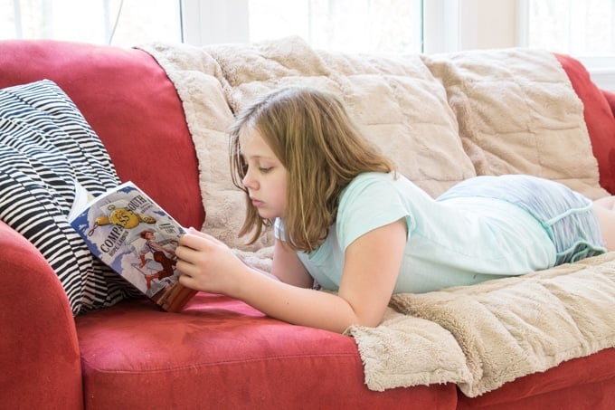 Girl reading graphic novels for summer reading.
