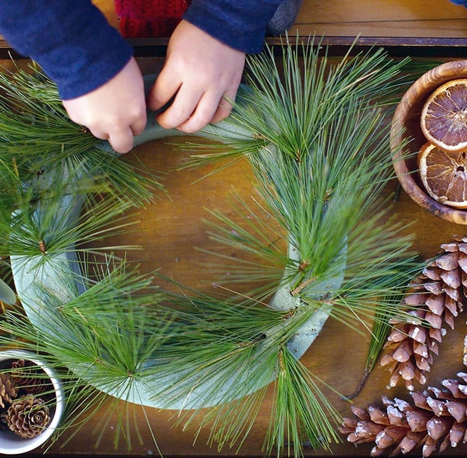 child adding greenery to foam wreath base_rachel
