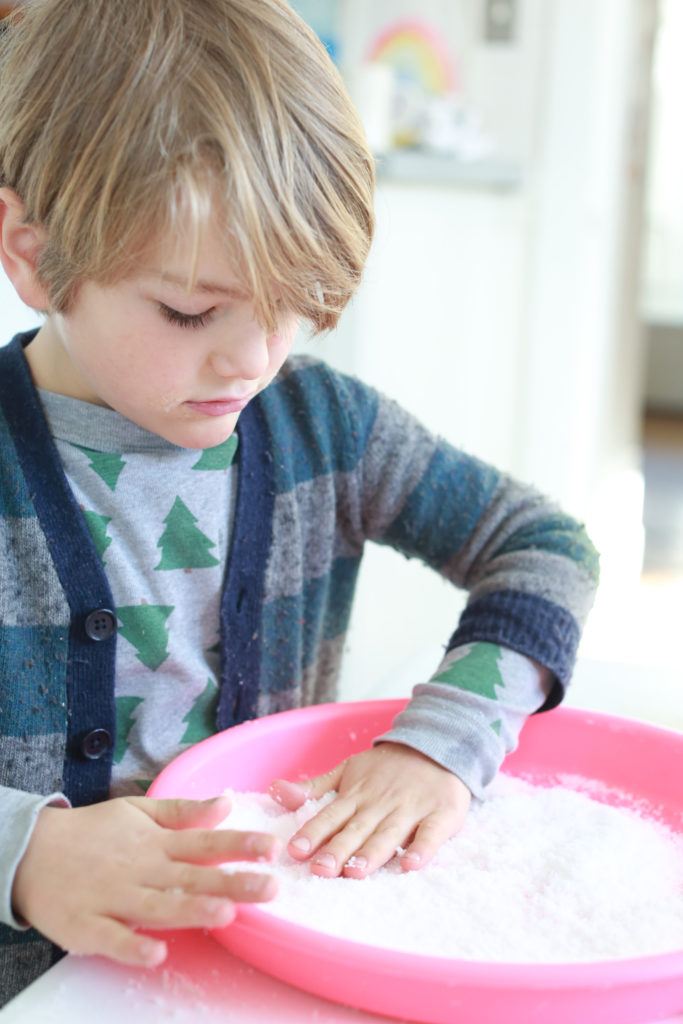 child pressing insta snow in tray