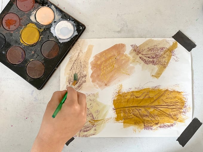 child painting leaf rubbings