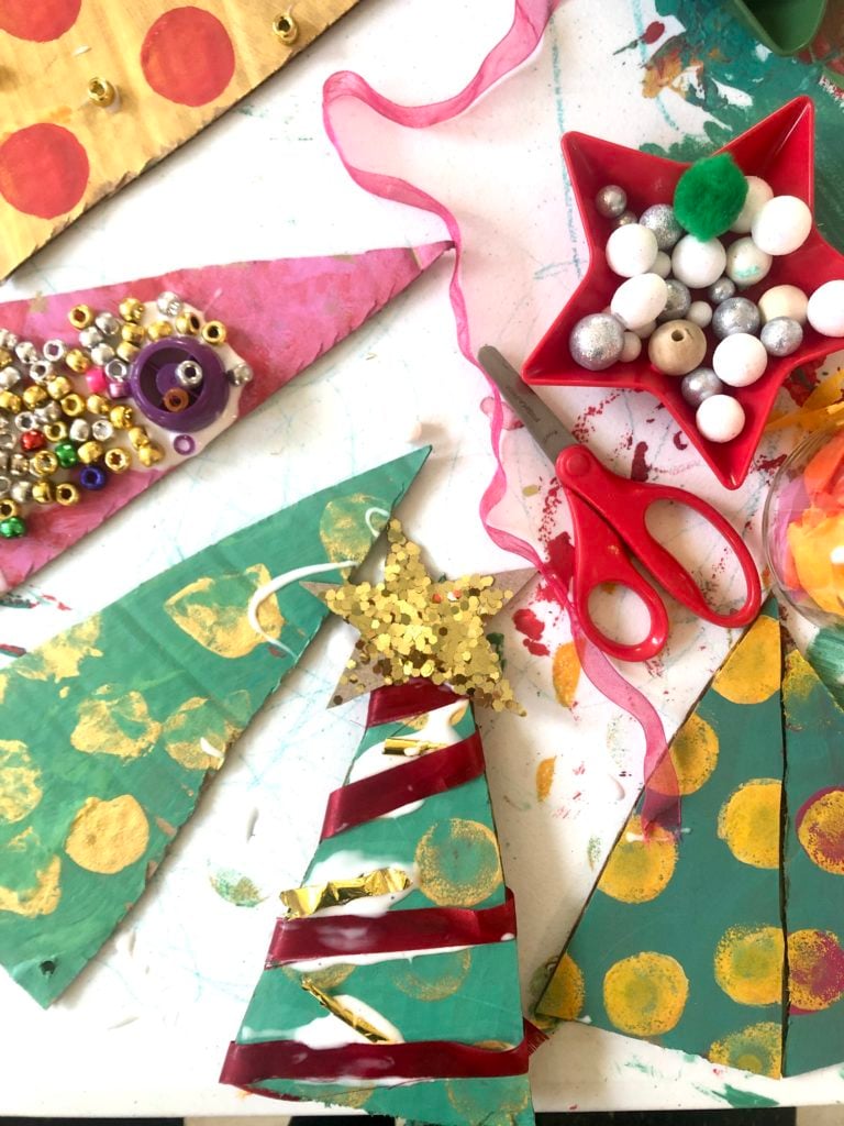 adding ribbon and stars to cardboard christmas trees
