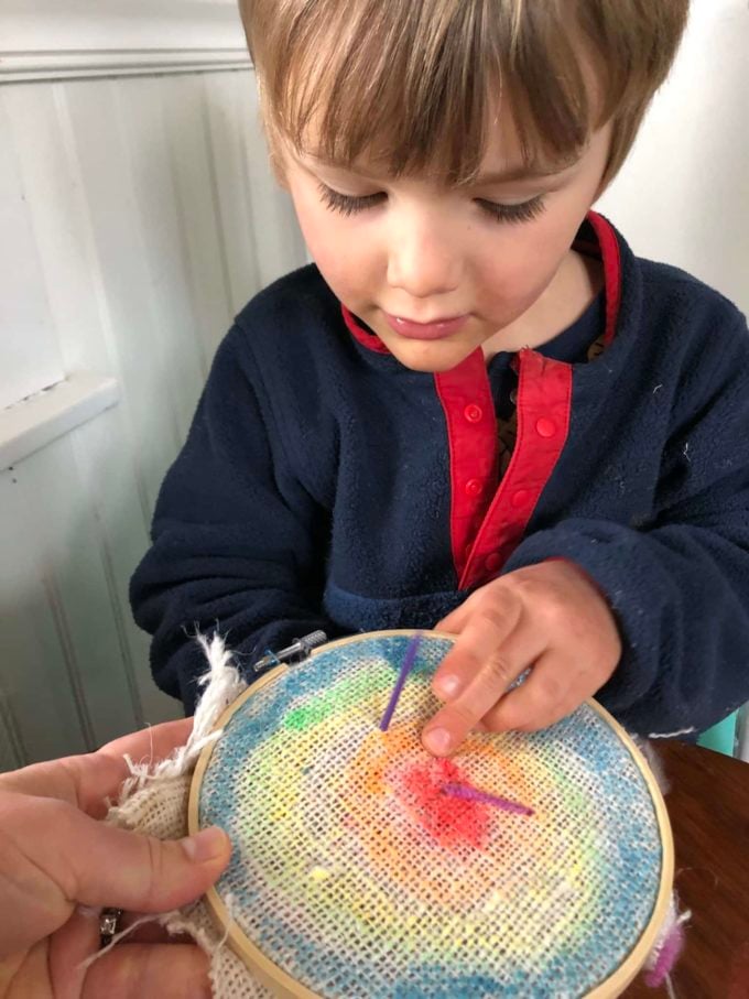 Child stitching burlap & beading