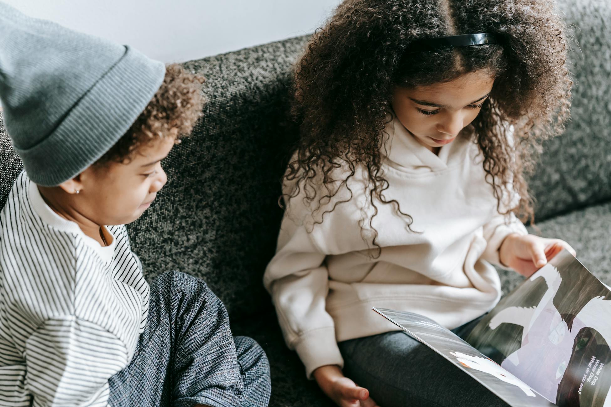 Two children looking down at the pages of a catalog together.