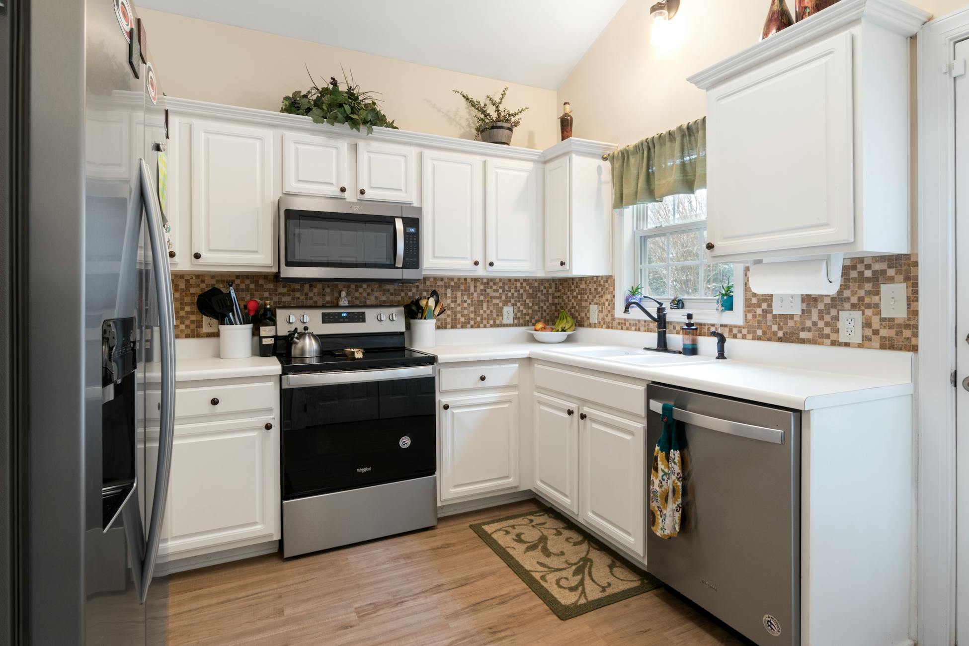 Spacious and well-lit kitchen featuring white cabinets and modern appliances.
