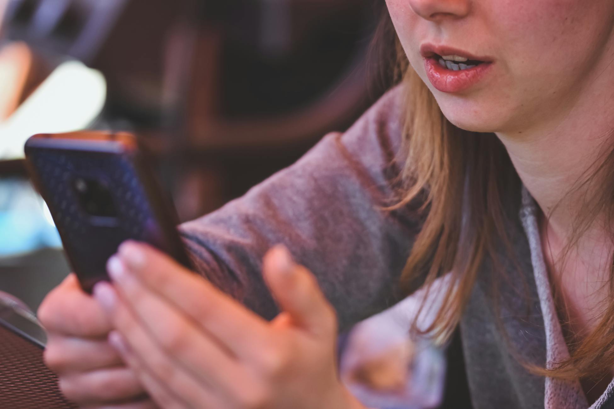 Close-up of woman using smartphone inside, demonstrating focus on mobile technology and communication.