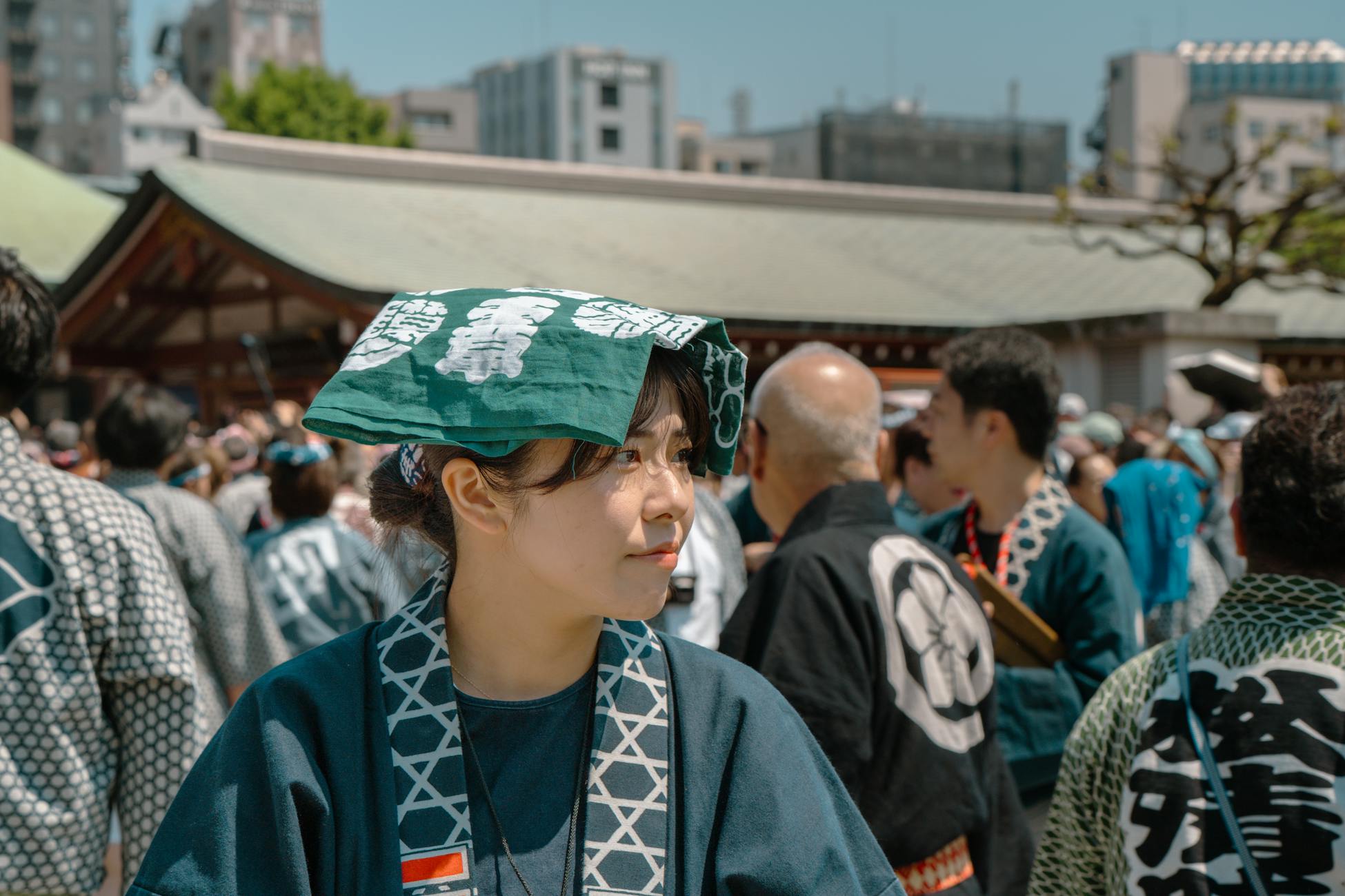 A woman in traditional attire at a vibrant Tokyo festival, surrounded by a lively crowd.