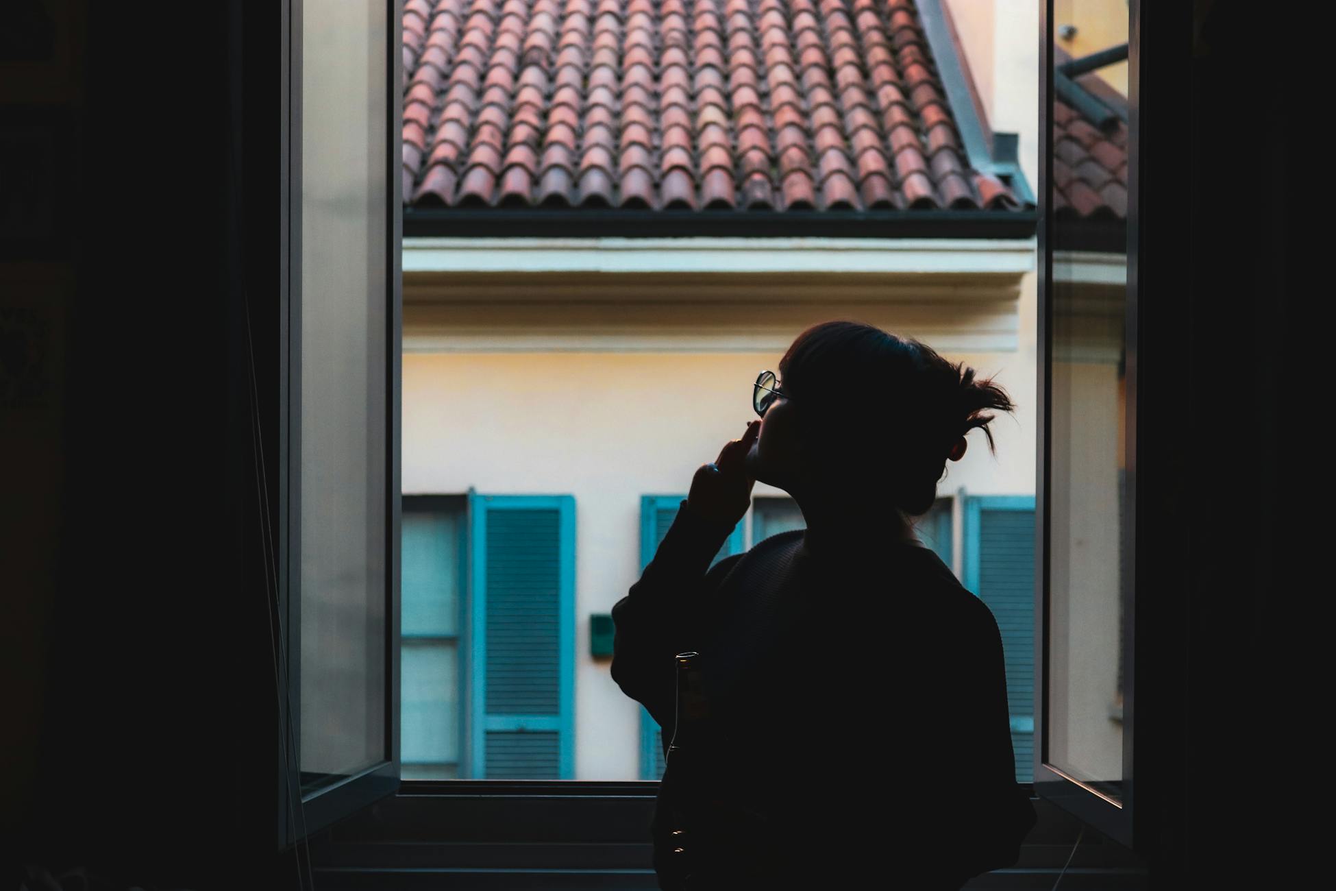 Silhouette of a woman in a quiet moment by the window.