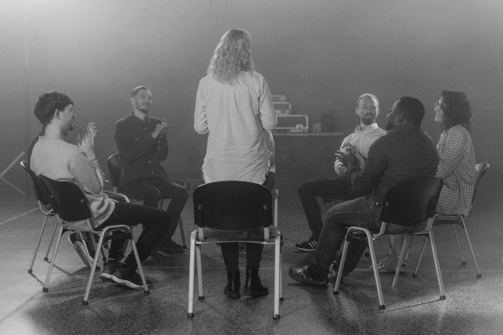 Black and white photo of a diverse group therapy session, fostering open discussion and support.