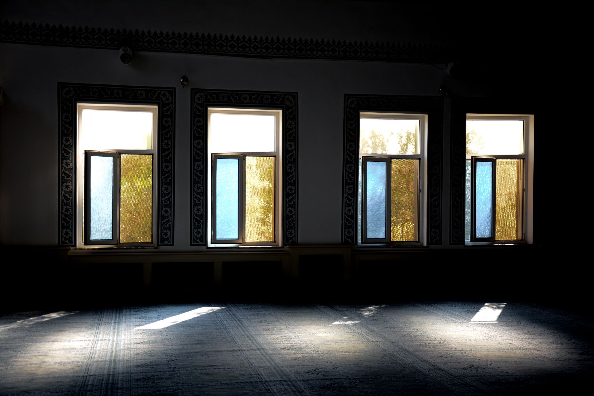Elegant room with large windows casting natural light onto patterned floor.