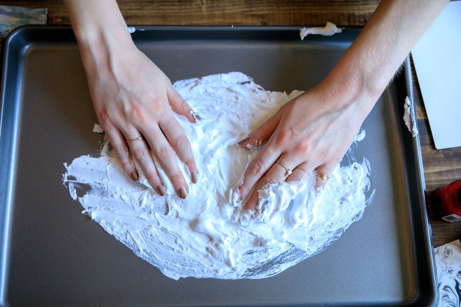 When a child drops food colouring onto a tray of shaving cream and drags a toothpick through the swirls, the pigment rides the foam's surface without sinking because whipped soap traps millions of tiny air bubbles — the same surface tension that lets water striders walk on a pond, now marbling paper on a kitchen bench.
